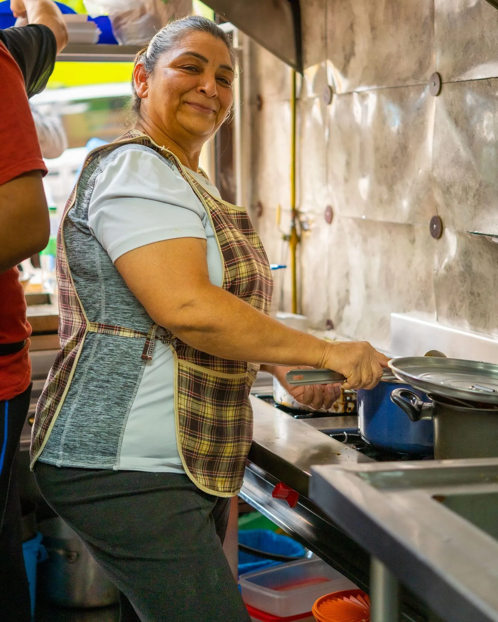 A woman smiling as she cooks in her kitchen