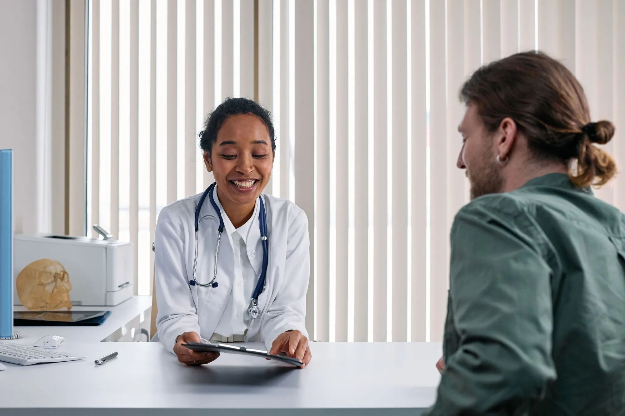 A doctor smiling as she talks with a patient