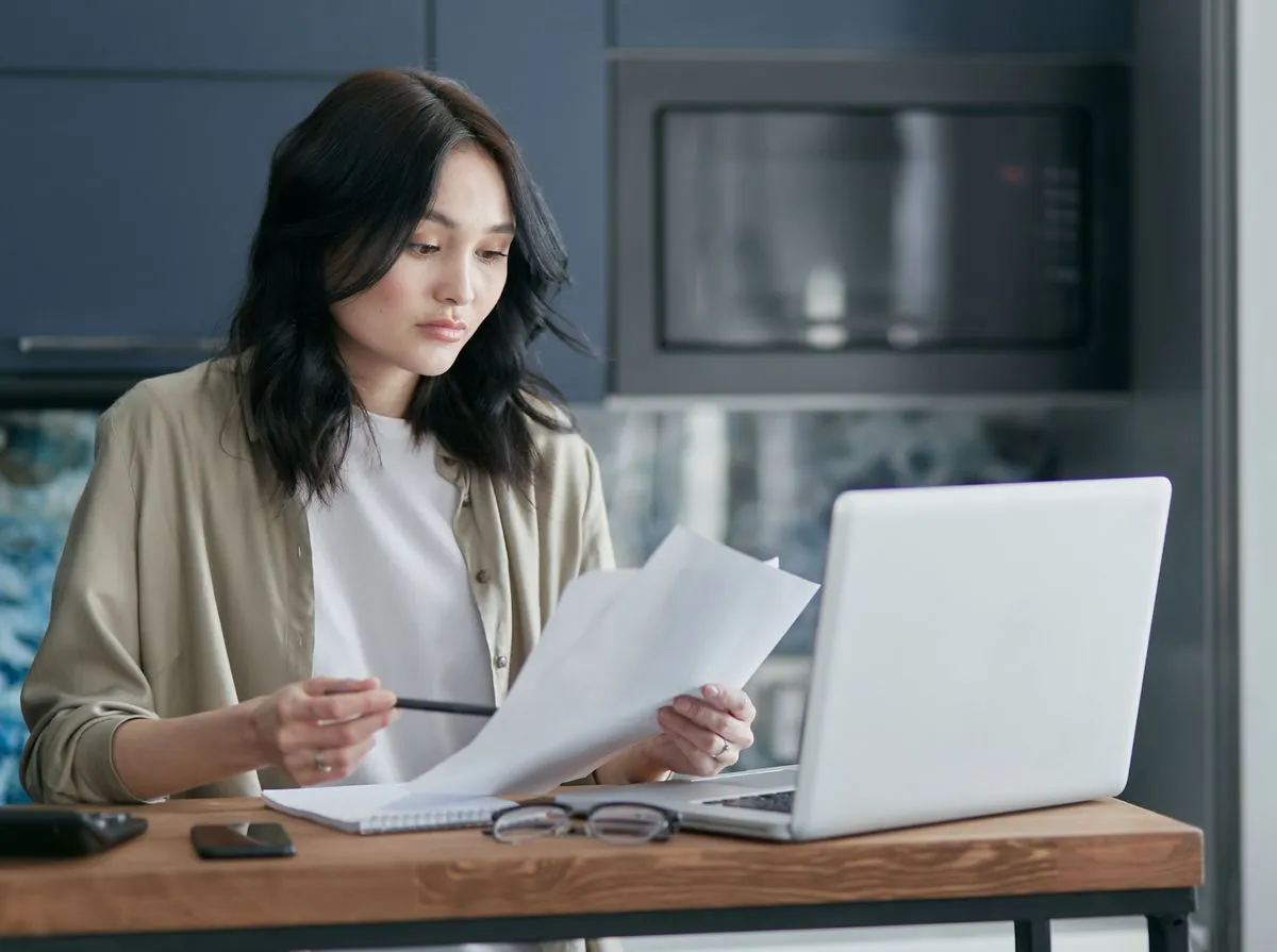 A woman reviewing paperwork at her kitchen table